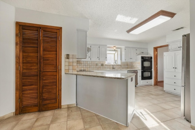 kitchen featuring light stone counters, kitchen peninsula, decorative backsplash, white cabinets, and black appliances