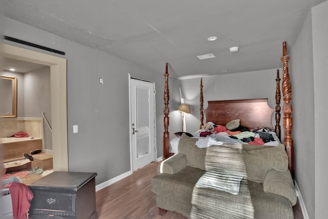 bedroom with wood-type flooring and a barn door