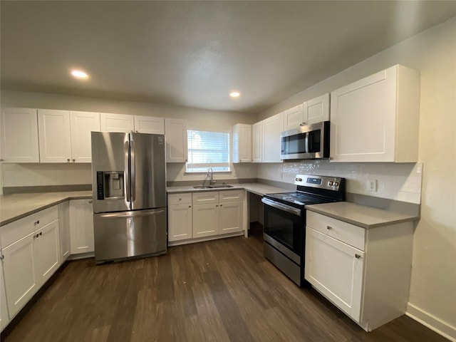 kitchen featuring white cabinets, appliances with stainless steel finishes, dark hardwood / wood-style floors, and sink