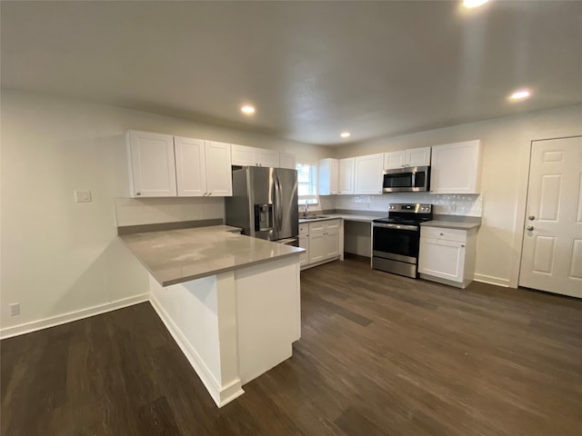 kitchen with kitchen peninsula, appliances with stainless steel finishes, white cabinetry, and sink