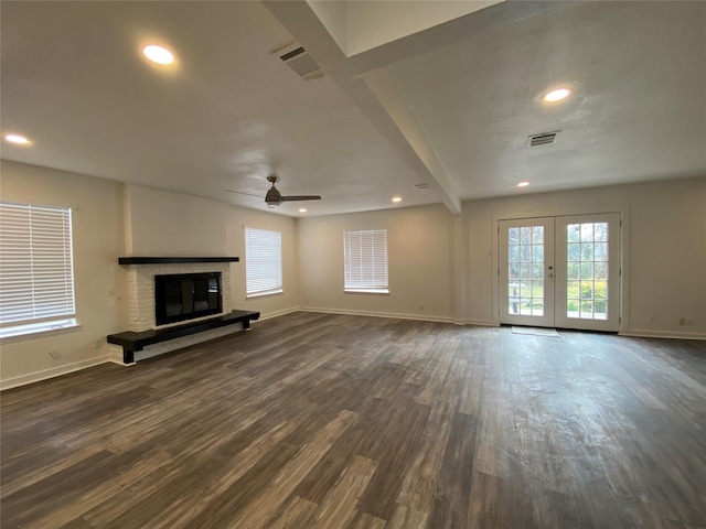 unfurnished living room with french doors, ceiling fan, dark hardwood / wood-style floors, a fireplace, and beamed ceiling