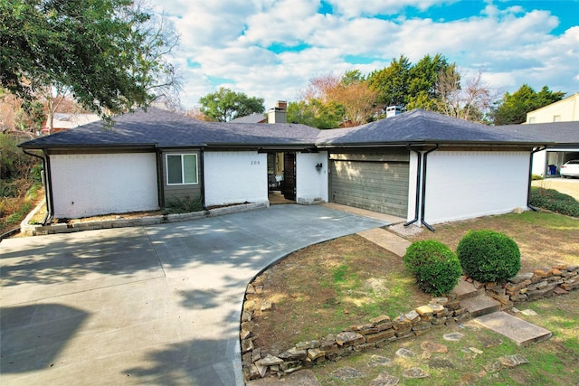 ranch-style home featuring a chimney, brick siding, a garage, driveway, and roof with shingles