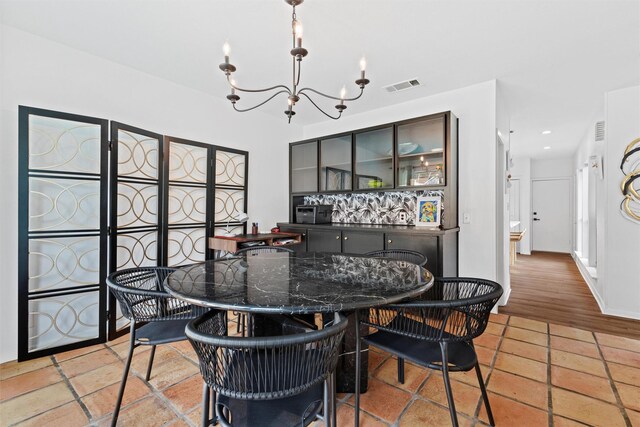 dining area with light tile patterned floors, a healthy amount of sunlight, and a notable chandelier