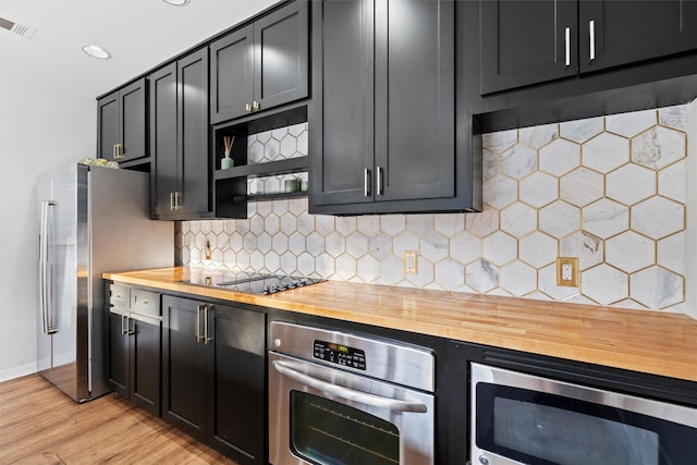 kitchen featuring wood counters, open shelves, light wood-style flooring, stainless steel appliances, and baseboards