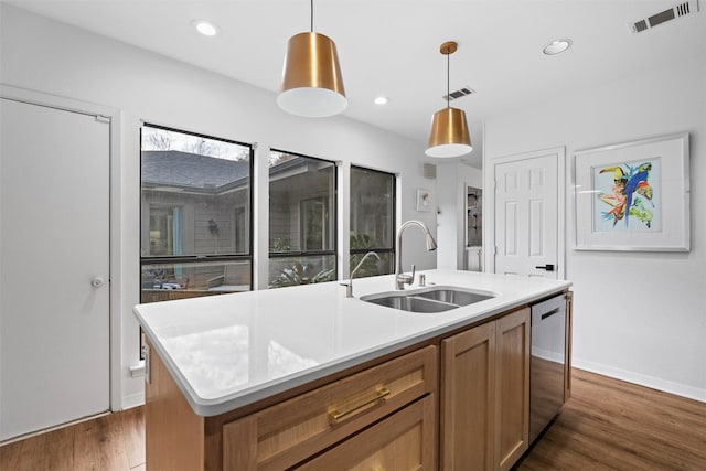 kitchen featuring dishwasher, sink, dark wood-type flooring, an island with sink, and pendant lighting