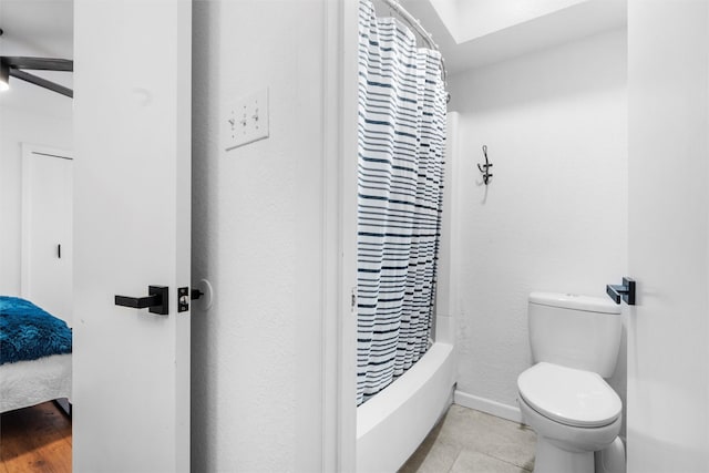 bathroom featuring toilet, ceiling fan, shower / bath combo with shower curtain, and baseboards