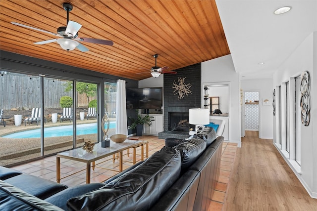 living room featuring wooden ceiling, light wood-style floors, a fireplace, a ceiling fan, and lofted ceiling