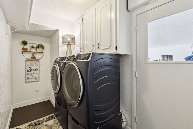 washroom with washer and dryer, a textured ceiling, and cabinets