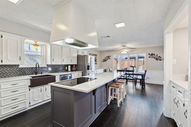 kitchen featuring a kitchen breakfast bar, a textured ceiling, stainless steel appliances, a kitchen island, and white cabinetry