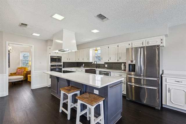 kitchen featuring a center island, stainless steel appliances, a kitchen bar, white cabinets, and custom range hood