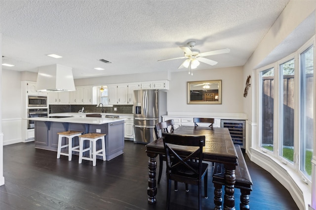 dining space featuring a textured ceiling, wine cooler, ceiling fan, and dark hardwood / wood-style floors