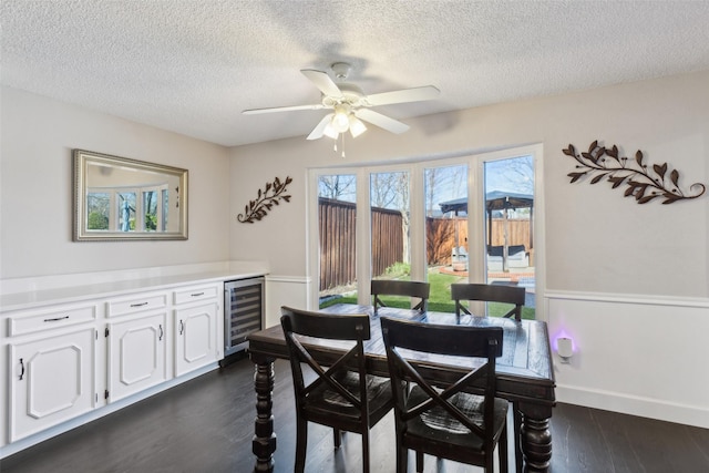 dining room with a textured ceiling, dark hardwood / wood-style floors, beverage cooler, and ceiling fan