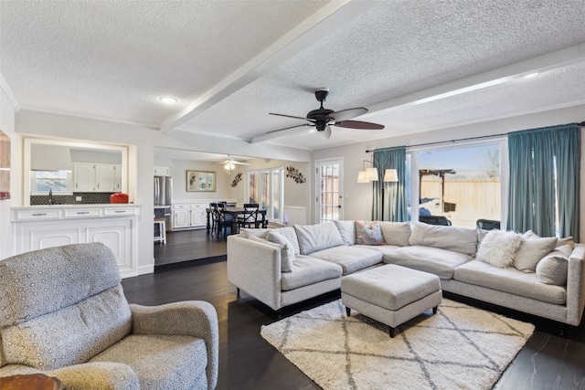 living room with ceiling fan, dark hardwood / wood-style flooring, beamed ceiling, and a textured ceiling