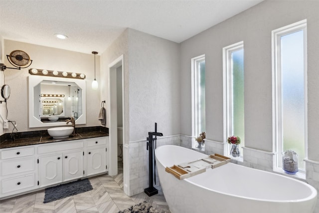 bathroom featuring a washtub, vanity, and a textured ceiling