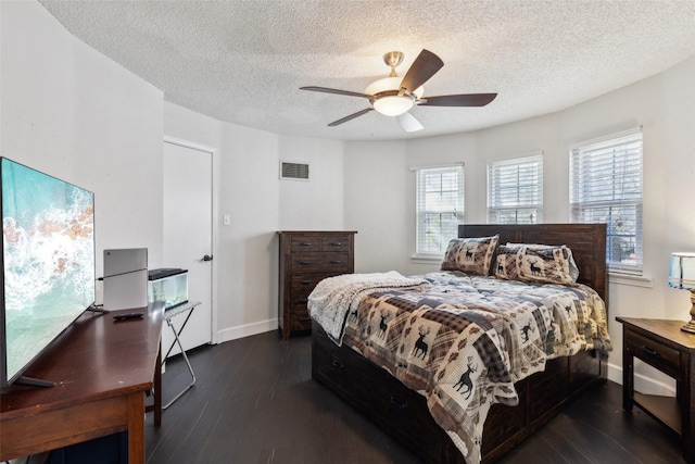 bedroom with a textured ceiling, ceiling fan, and dark wood-type flooring