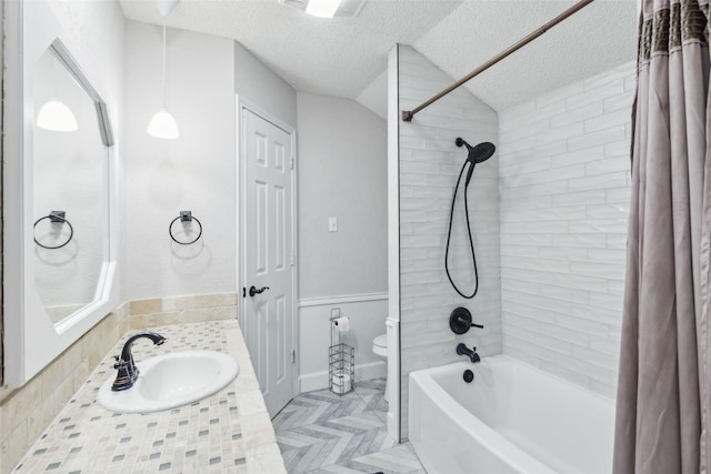 full bathroom with vanity, vaulted ceiling, toilet, shower / bath combo with shower curtain, and a textured ceiling