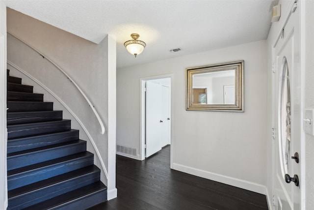 entrance foyer featuring a textured ceiling and dark wood-type flooring