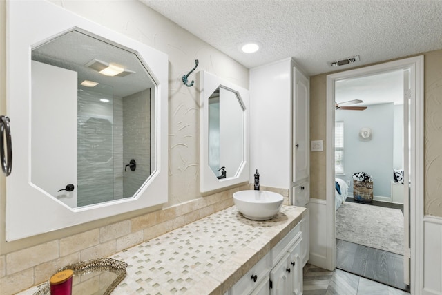 bathroom with a textured ceiling, vanity, and ceiling fan