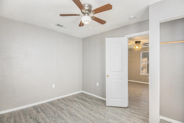 empty room with ceiling fan and light hardwood / wood-style floors