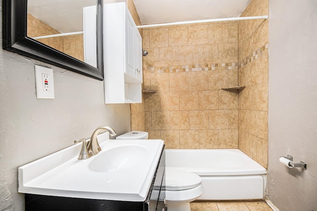 full bathroom with tile patterned flooring, tiled shower / bath, vanity, and toilet