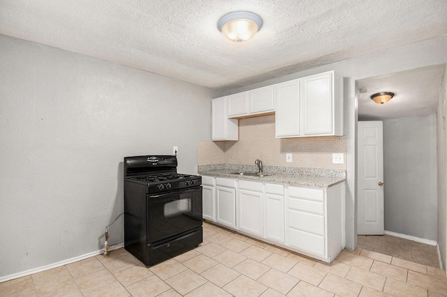 kitchen with sink, black gas stove, backsplash, light stone counters, and white cabinets