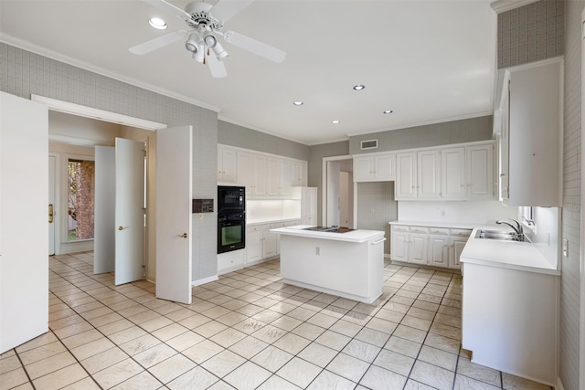 kitchen with sink, crown molding, white cabinetry, black appliances, and a kitchen island