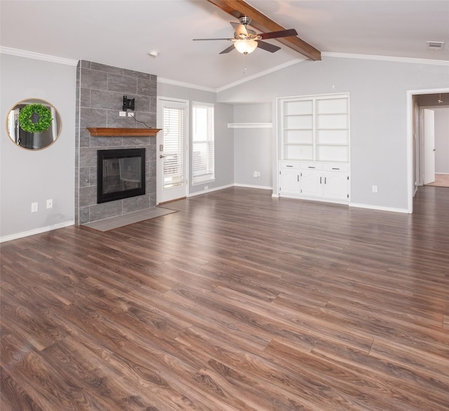 unfurnished living room with crown molding, dark hardwood / wood-style flooring, a tiled fireplace, and vaulted ceiling with beams