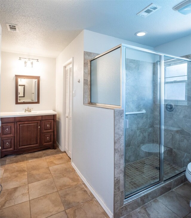 bathroom featuring vanity, an enclosed shower, toilet, and a textured ceiling