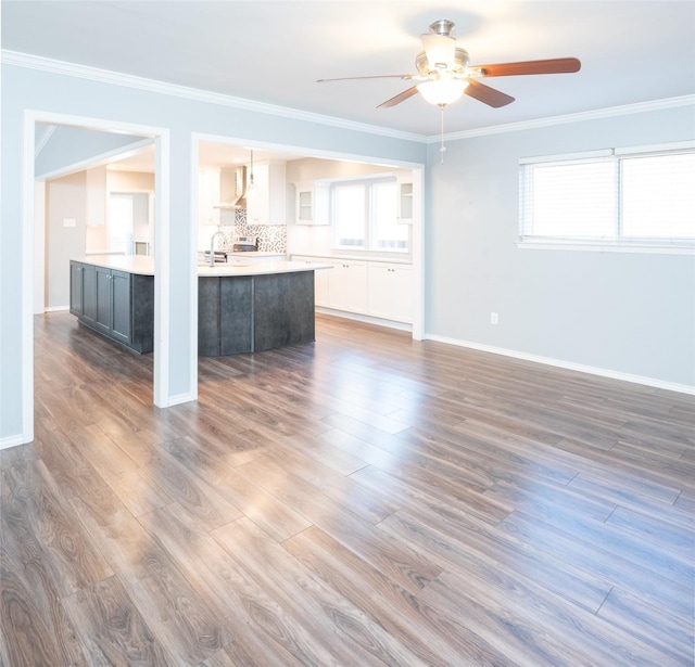 unfurnished living room featuring crown molding, ceiling fan, sink, and hardwood / wood-style flooring