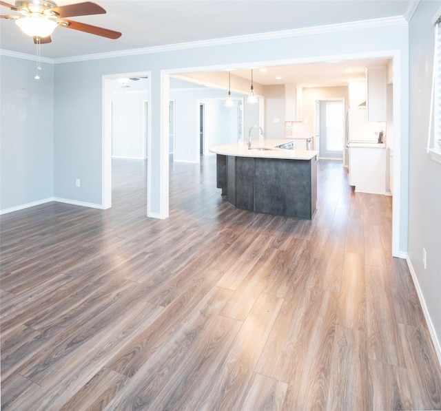 interior space featuring sink, a kitchen island with sink, white cabinets, dark hardwood / wood-style flooring, and decorative light fixtures