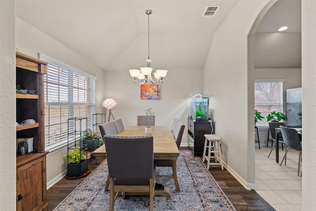 dining area with a notable chandelier, dark hardwood / wood-style floors, and vaulted ceiling