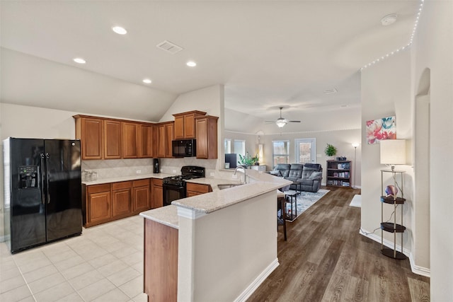 kitchen featuring black appliances, sink, vaulted ceiling, ceiling fan, and kitchen peninsula