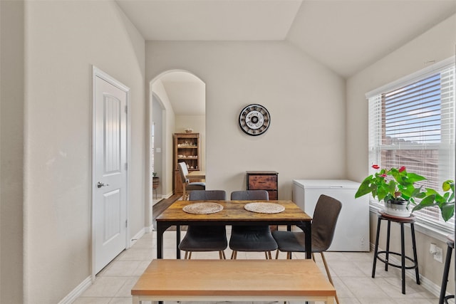 tiled dining space with lofted ceiling