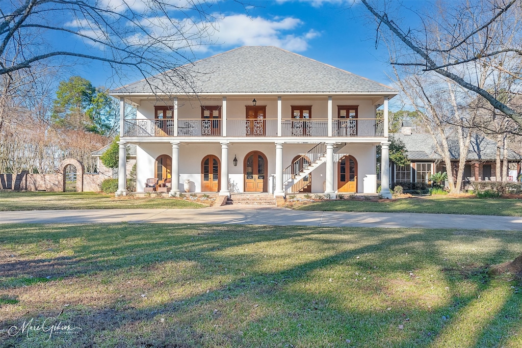 view of front of house with a balcony, a front yard, and covered porch