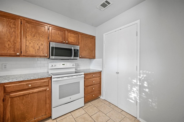 kitchen featuring tasteful backsplash, electric range, light tile patterned floors, and light stone counters