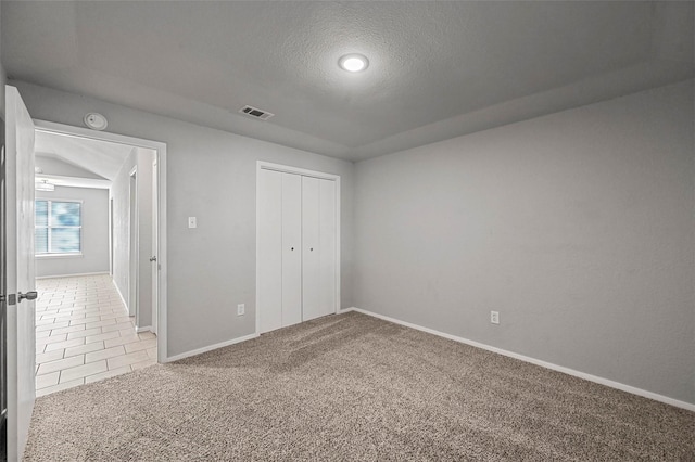 unfurnished bedroom featuring carpet, a textured ceiling, and a closet