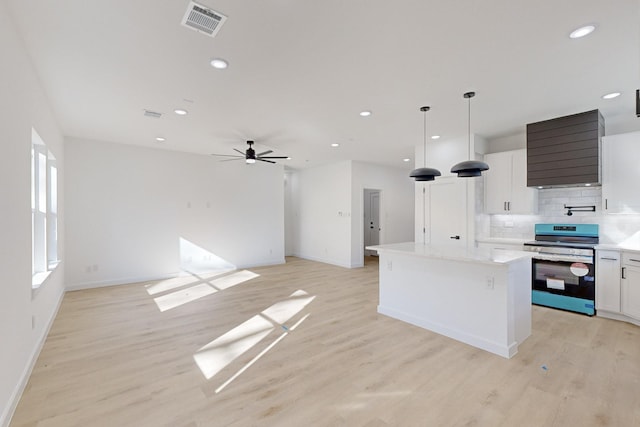 kitchen with decorative backsplash, decorative light fixtures, white cabinets, stainless steel stove, and a kitchen island