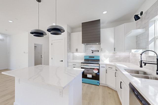 kitchen featuring sink, stainless steel appliances, a kitchen island, decorative light fixtures, and white cabinets