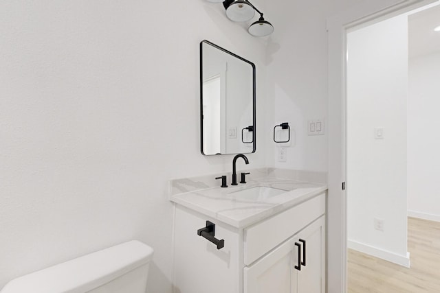 bathroom featuring wood-type flooring, vanity, and toilet