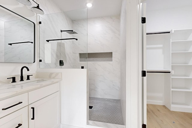 bathroom with tiled shower, vanity, and hardwood / wood-style flooring