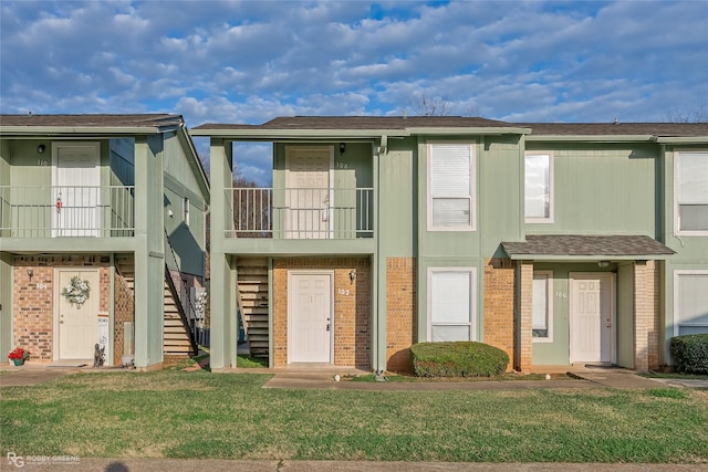 multi unit property with a balcony and a front lawn