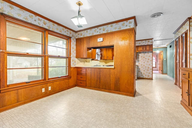 kitchen featuring wood walls, ornamental molding, and hanging light fixtures