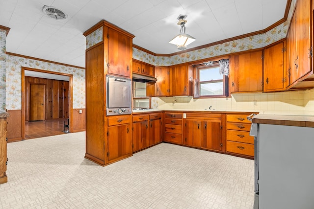 kitchen with gas cooktop, oven, ornamental molding, and sink