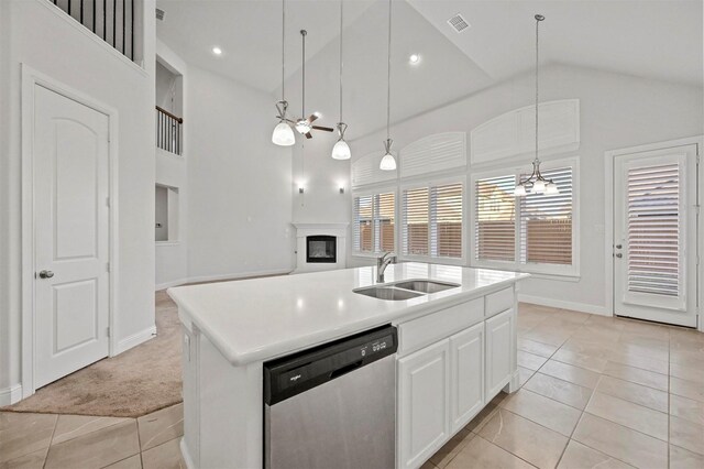 kitchen with pendant lighting, a center island with sink, stainless steel dishwasher, light tile patterned floors, and white cabinetry