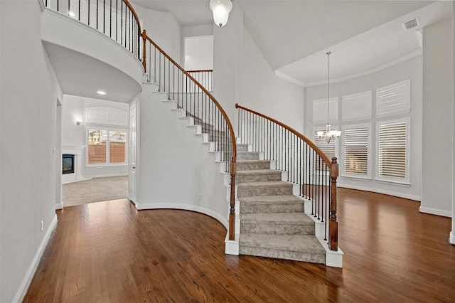 entryway with dark hardwood / wood-style flooring, crown molding, and an inviting chandelier