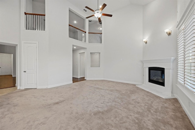 unfurnished living room featuring carpet floors, high vaulted ceiling, and ceiling fan