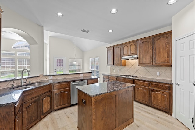 kitchen with a center island, hanging light fixtures, sink, decorative backsplash, and appliances with stainless steel finishes