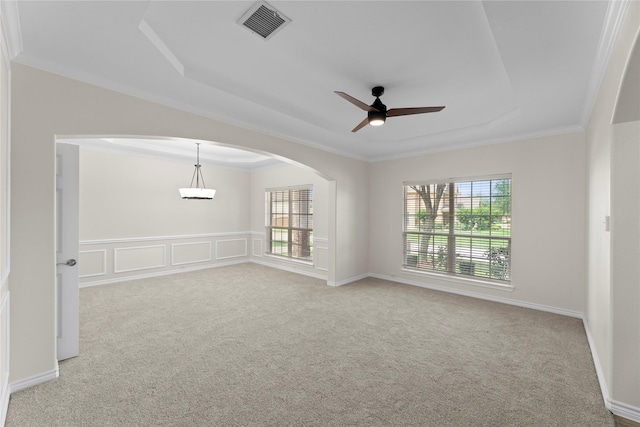 carpeted spare room featuring ceiling fan, ornamental molding, and a tray ceiling