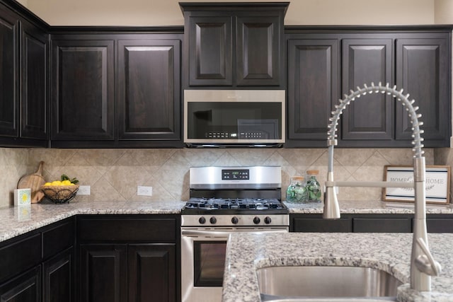 kitchen with tasteful backsplash, light stone counters, and appliances with stainless steel finishes