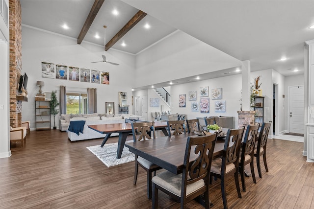 dining space featuring ceiling fan, a towering ceiling, hardwood / wood-style floors, and beam ceiling